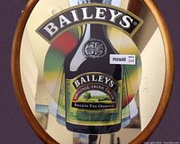 Close-up photo of the oval vintage advertising mirror showing the Baileys bottle image and wooden frame.