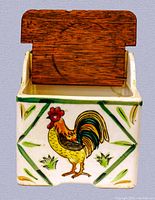 Front view of the vintage ceramic salt box showing the colorful rooster artwork and wooden lid.