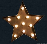 Front view of the star-shaped marquee sign showing 11 light bulbs arranged evenly on a gold or brass colored metal star.