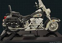 Side view showing detailed Harley Davidson motorcycle telephone with black body, white and silver accents, saddlebags, and chrome engine parts on black base.