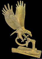 Front angle view of the vintage brass eagle landing statue on a textured tree branch base, showing detailed feathers and talons.