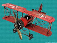 Front angle view of vintage WW1 Fokker Red Baron tin biplane with red wings and propeller