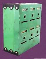 Side angled view of green metal Home Budget Bank coin bank showing black corner guards and wear marks.