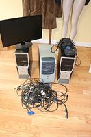 Full view of the three desktops, monitor on top of one desktop, black keyboard on another, and cables in front.