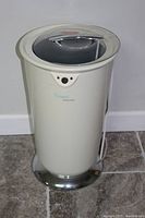 Front view of the white cylindrical towel warmer showing the transparent lid, control panel, and chrome base.