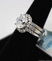 Close-up front view showing the large clear central simulant diamond and smaller stones along the triple silver band.