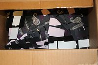 Box showing numerous Pink Pewter Bailey bobby pin sets on black and pink packaging cards inside a cardboard box