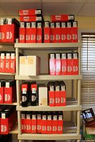 White shelving unit with multiple red G-Force Racing Gear Racing Suit boxes across four shelves