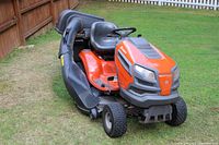 Left-front perspective showing mower body, seat and attached grass collection bags