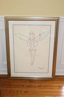 Full view of framed Tinkerbell sketch print leaning against wall