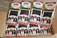 Top-down view of multiple boxed packs of human hair weave extensions inside a larger cardboard box. Each pack contains 4 pieces, displayed with clear windows showing the curled hair style and labeled Beach Curl 4PCS.
