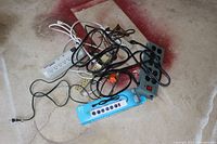 Photo showing five different surge protectors and power strips tangled together, varied brands and outlet counts visible