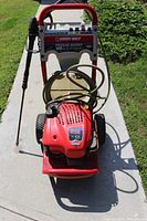 Front view of Troy-Bilt pressure washer showing hose wrapped on frame, and spray wand mounted on side.