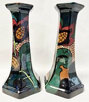 Pair of DECORO ceramic candleholders side by side showing the floral design and hexagonal shape.