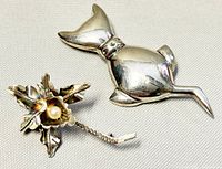 Two 925 silver brooches: a cat-shaped brooch and a flower-shaped brooch with a small central pearl, shown from front and back.