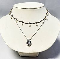 Front view of both necklaces displayed on bust, showing pearl choker and silver pendant necklace