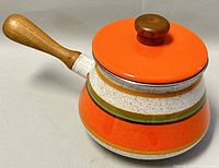 Side view of enamel pot with wood handle and orange lid knob resting on lid.