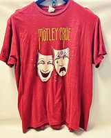 Front side of Motley Crue red graphic T-shirt, red color with theatrical mask graphics and band name.