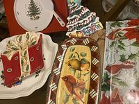 Top view of assorted Christmas-themed serving platters including tree plate, segment dish with holly, rectangular cardinal tray, tall cardinal platter