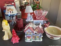 Multiple Christmas-themed candles and candle holders shown on indoor surface with varied designs and colors.