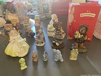Group photo showing a variety of small figurines including bears, angels, and animals arranged on a table