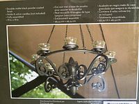 Photo of the chandelier on the product box illustrating the item fully assembled, showing the powder-coated black metal with scrollwork and candle holders.