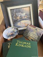 Photo showing textured framed print, two Thomas Kinkade books, an oval Bradford Exchange plate, and a packaging box for a Bradford Exchange plate.