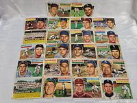 Front view of 22 assorted 1956 Topps baseball cards laid out on a flat surface showing colorful player portraits and action shots.