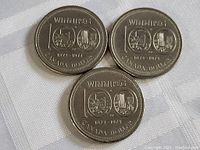 Three 1974 Winnipeg Canada dollar coins displayed on a white textured fabric, showing the front commemorative side with locomotive and cityscape designs