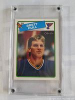 Front view of the 1988-89 OPC Brett Hull rookie card inside a clear screw-down protective case on a fabric background.