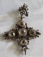 Front view of the pendant showing the five large faceted clear gemstones set in ornate metal filigree with a darkened patina.