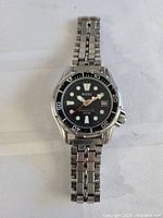 Full view of BUND men's professional divers watch with stainless steel bracelet and black dial on white surface.