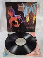Vinyl record with label viewed on top of album cover and printed inner sleeve visible beneath.
