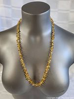 Full view of amber necklace displayed on a mannequin bust showing the length and drape of the necklace.