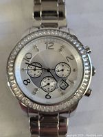 Front-facing photo of Silpada men's dress chronograph watch with silver-tone band, clear stones around bezel, and visible subdials and date window on dial.