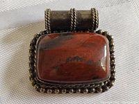Close-up top view of the rectangular jasper stone with silver beaded border and unique bail with twisted wire decoration, showing natural patina.