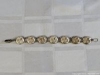 Full view of sterling silver bracelet laid flat showing round spider-themed medallions linked in sequence.
