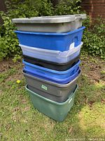 Stacked view of 8 plastic storage totes without lids showing various colors and signs of use.