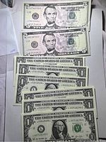 Photo showing five $5 bills featuring Abraham Lincoln, each crisp and uncirculated.