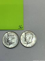 Obverse side of two 1966 Kennedy half dollar coins showing JFK profile and inscriptions.