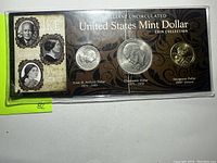 Front side of the sealed coin collection showing the three coins and decorative packaging.