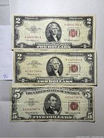 Front side of two $2 Red Seal notes and one $5 Red Seal note showing portraits and red seals.