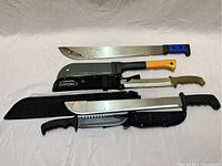 Overview of five large cutting utensils with handles in various colors and different blade types laid on white background