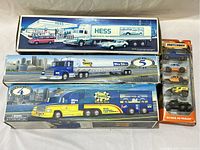 Photo showing three boxed toy trucks (Hess, Sunoco tanker, Sunoco racing truck) and a package of Matchbox cars