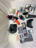 Full overview of lot showing controllers, cartridge cases, gun accessory, wired headset, game cartridges, and game disc.