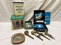 Overview showing ashtrays, tobacco pipes, and various vintage tobacco tins including Blend of the Month and Red Man