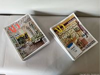Two stacks of Architectural Digest magazines on a white surface, showing colorful covers with interior design photos.
