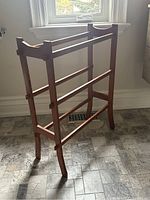 Full side view of the wooden towel rail showing its height, multiple horizontal rails, and curved design details.