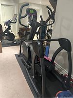 Three-quarter side view showing frame, pedals, handles, console, and nearby equipment