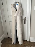 Four fabric bolts arranged upright against a white door cornered on a wooden floor, showing varied colors and textures.